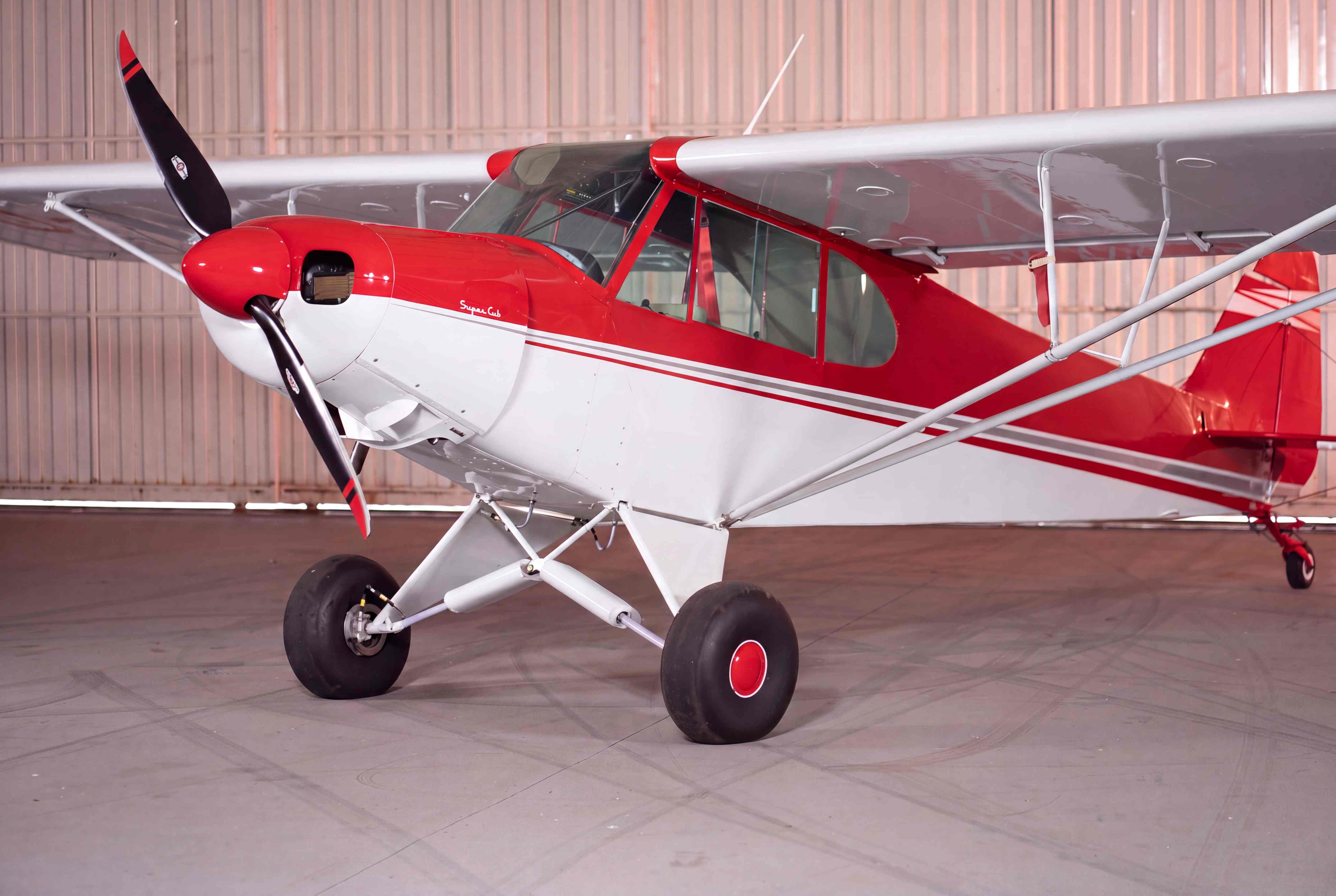 Avião Cerejinha vermelho e branco estacionado no hangar